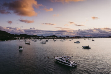 Many moored yachts off the coast at sunset.
