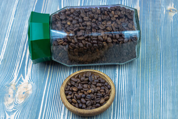 A jar of black unground coffee and wooden utensils with coffee.