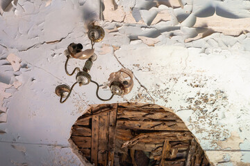 Collapsed ceiling in an old building. An old lamp hangs.