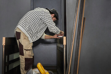 Preparing the door for installation. A man installs a door handle