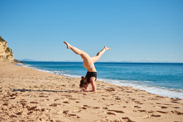 Fototapeta na wymiar A closeup of a young woman doing a yoga on the beach