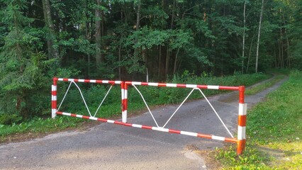 Obraz na płótnie Canvas The metal gates at the exit from the paved highway to the forest dirt road are locked. This is done during the summer dry and fire-hazardous period to prevent forest fires. Grass and trees grow along 