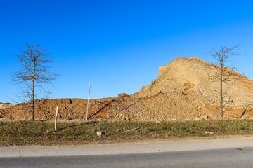 Travaux et évacuation de terre sur un chantier en bord de route, sur fond de ciel bleu au...