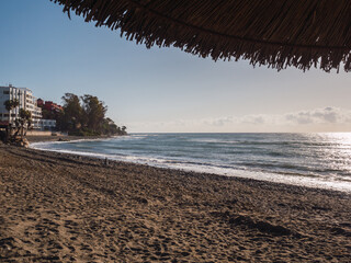 Fototapeta premium Mediterranean south beach in Estepona, Spain; next to an umbrella and with the city to one side