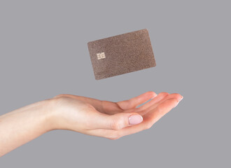 Woman hand and levitating plastic bank or debit card. Cashless payment and booking, making purchases on credit. High quality photo - obrazy, fototapety, plakaty