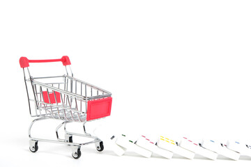 Shopping cart and fallen dominoes white background.