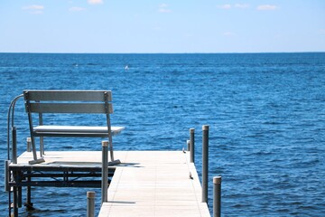 Fototapeta na wymiar Pier with bench at the blue lake