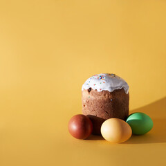 Close-up of coloured Easter eggs and easter cake or kulich on a yellow background. With a space to copy. High quality photo