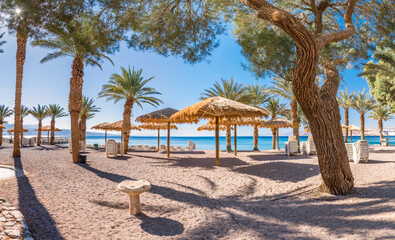 Fototapeta na wymiar Morning on sandy beach of the Red Sea in Eilat - famous tourist resort and recreational city in Israel. Concept of bliss vacation and happy holiday 