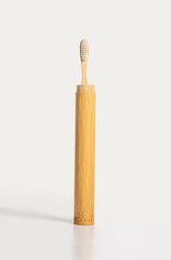 An upright bamboo toothbrush on a light background. A zero-waste or low-waste alternative to plastic.