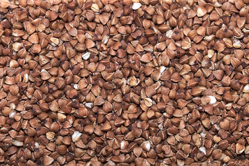 Brown buckwheat grains close-up, surface with textured background