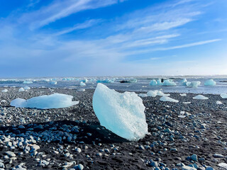Icy coastal landscape in a shore of Iceland, full of big pieces of ice on the beach and floating in the water. 