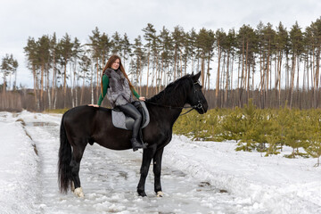 Girl with red hair riding a horse. Winter walk with your beloved pet