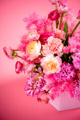 Beautiful bouquet of pink, white and green flowers close-up on a pink background