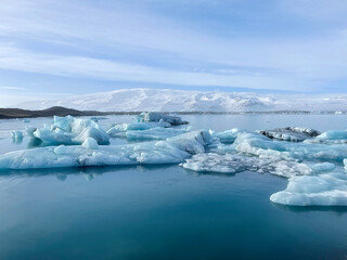 Icy coastal landscape in Iceland, full of big pieces of ice on the beach and floating in the water. 
