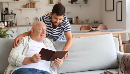 Man and his senior father reading book at home