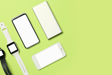 Mobile phones, power bank and smart watches on green background, closeup