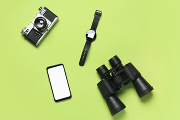 Mobile phone, binoculars, smart watch and photo camera on green background