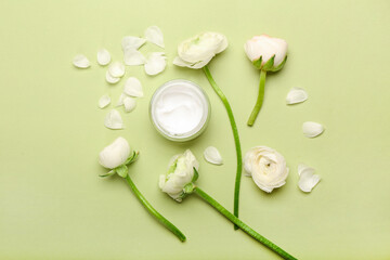 Composition with jar of cosmetic product and ranunculus flowers on green background