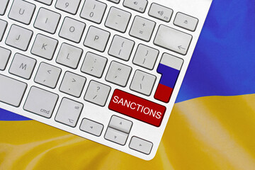White computer keyboard with button of flag Russia and red button with word of sanctions on Ukraine...