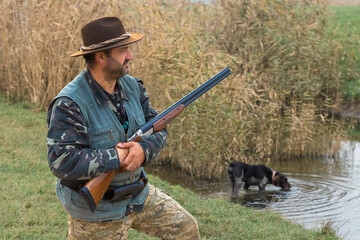 Hunter man in camouflage with a gun during the hunt in search of wild birds or game. Autumn hunting...