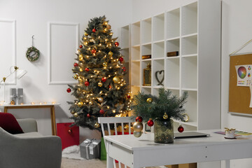 Modern workplace with fir branches in room decorated for Christmas