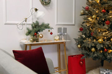 Vase with fir branches, Christmas balls, lamp and gift on table in room