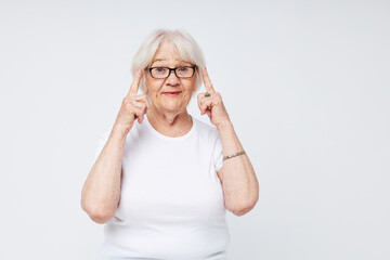 emotional elderly woman in casual t-shirt and glasses light background