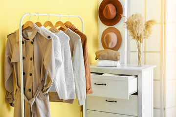 Rack with warm clothes near yellow wall in hall