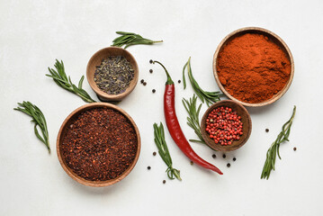 Wooden bowls with different spices and herbs on light background