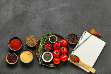 Composition with different spices, tomatoes and notebook on dark background