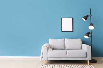 Fototapeta na wymiar Stylish sofa and lamp near blue wall