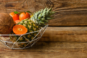 Basket with juicy fruits on wooden background, closeup