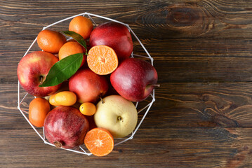 Basket with juicy fruits on wooden background