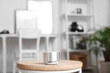 Wireless portable speaker on wooden table in light room