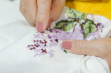 Older adult woman embroidering.