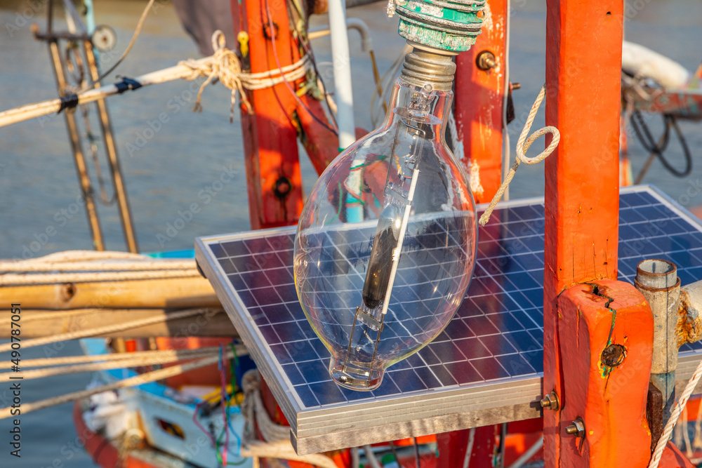 Poster A halogen lamp with a solar battery charging station on the deck of a fisher boat