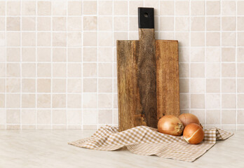 Obraz na płótnie Canvas Wooden cutting boards and onion on table near tile wall