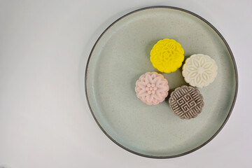 An assortment of colorful mini snow skin mooncakes on a green serving plate