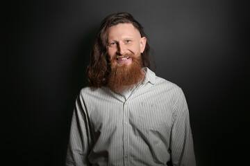 Portrait of handsome happy bearded man on dark background