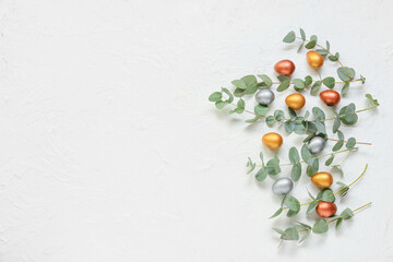 Composition with Easter eggs and eucalyptus branches on light background