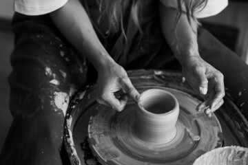 Young woman doing handmade pottery on the potter's wheel. Artist at work - obrazy, fototapety, plakaty