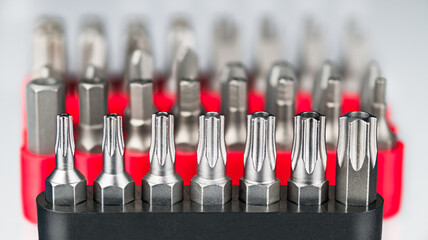 Fototapeta premium Closeup of metal torx, hexagon or pozidriv screwdrivers toolkits on white blurry background. Steel star bits set and different screw drivers kit of varied sizes in black or red box in artistic detail.
