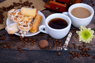 two cups of coffee, black and with milk, coffee grinder, cookies and coffee beans