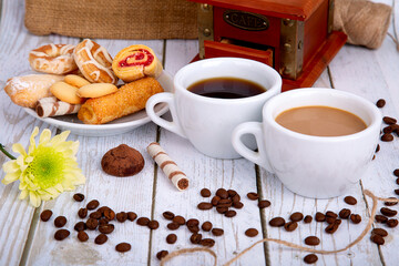 two cups of coffee, black and with milk, coffee grinder, cookies and coffee beans