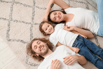 Happy young family lying on soft carpet at home