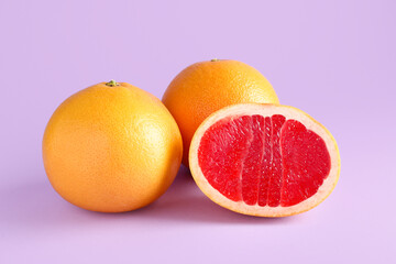 Tasty ripe grapefruits on purple background