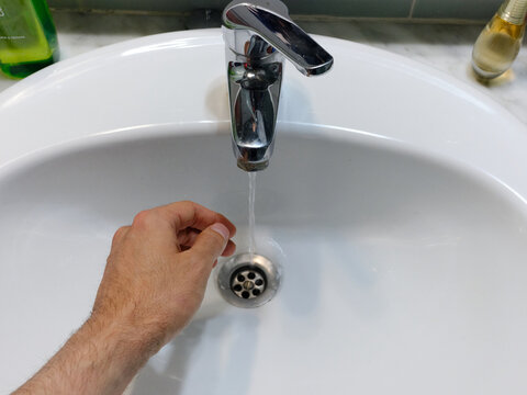 Hand On A Sink With Water Running Out Of The Faucet