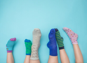 Feet of mothers and children with socks in different colors on a light blue background. Family...