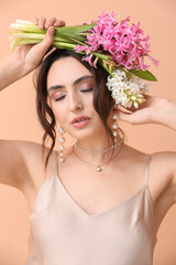 Pretty young woman with hyacinth flowers on color background